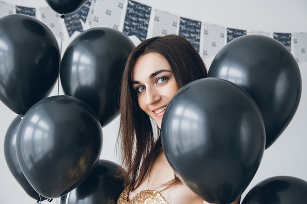 Girl in a gold dress with black balloons