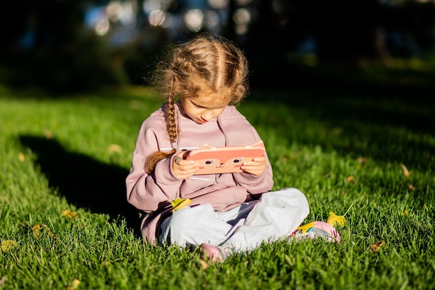 A girl on a green lawn with a gadget in her hands