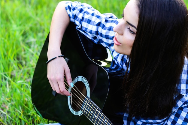 Girl on a green meadow playing guitar