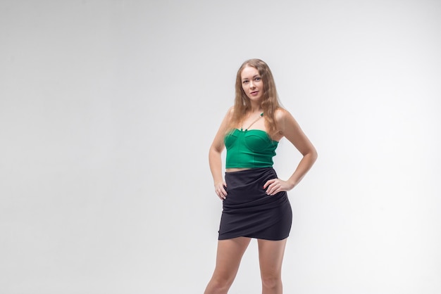 Photo girl in green top and black skirt in white studio