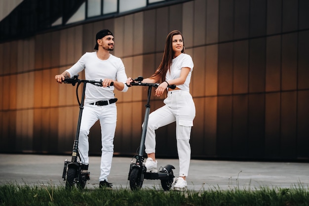 A girl and a guy are walking on electric scooters around the city, a couple in love on scooters.