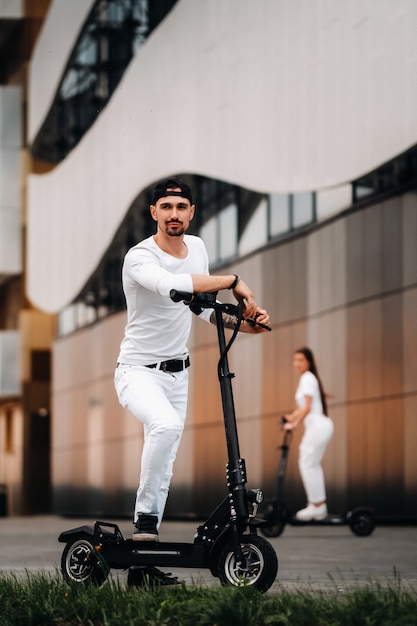 A girl and a guy are walking on electric scooters around the city, a couple in love on scooters