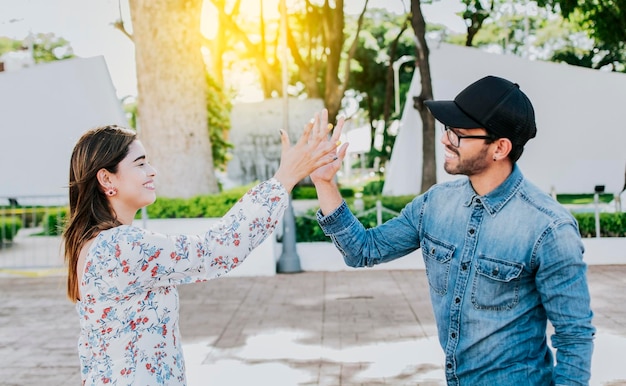 A girl and a guy shaking hands on the street Two young smiling teenagers shaking hands in the street Concept of man and woman shaking hands on the street