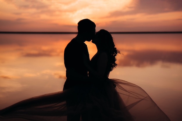 Girl and a guy on the shore of a pink salt lake at sunset