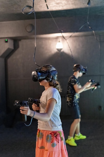 A girl and a guy in virtual reality helmets with joysticks play computer 3D games