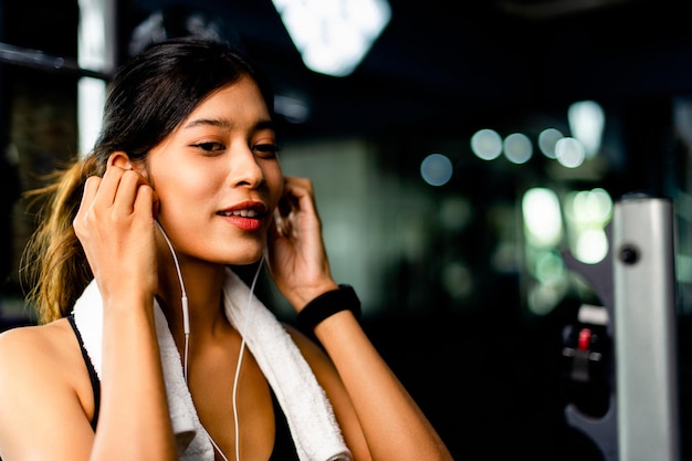 Girl in the gym exercising use a cell phone Listening to music with white headphones and using a digital heartbeat timer systematic exercise her vacation relaxation