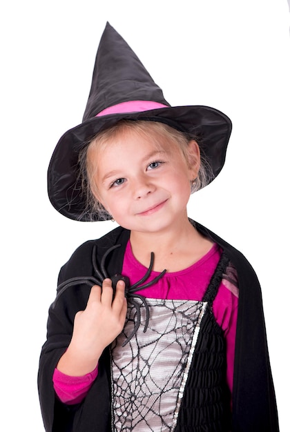 A girl in a halloween costume holds a black toy spider in her hands on a white background