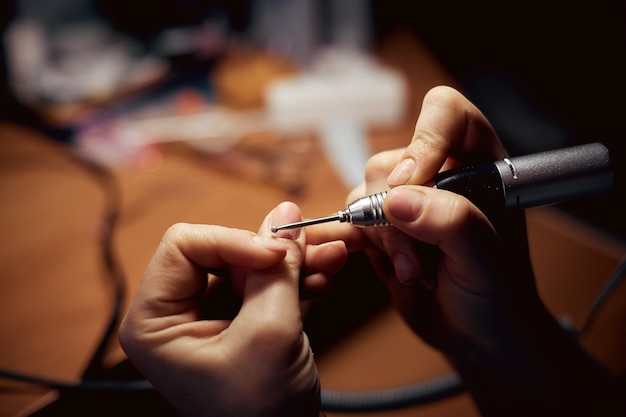 Girl handles nails with a milling cutter for manicure