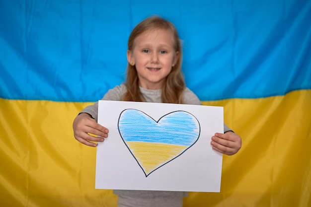 Girl hands holding banner with drawn yellowblue heart on Ukrainian flag Stop war staywithUkraine