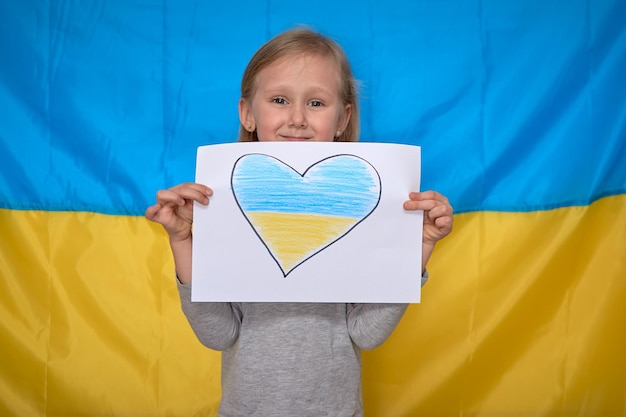 Girl hands holding banner with drawn yellowblue heart on Ukrainian flag Stop war staywithUkraine