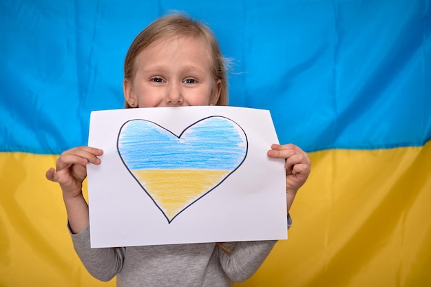 Girl hands holding banner with drawn yellowblue heart on Ukrainian flag Stop war staywithUkraine