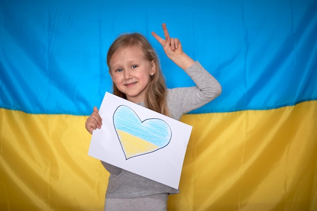 Girl hands holding banner with drawn yellowblue heart on Ukrainian flag Stop war staywithUkraine