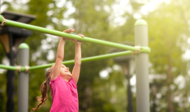 the girl happily hung on the horizontal bar