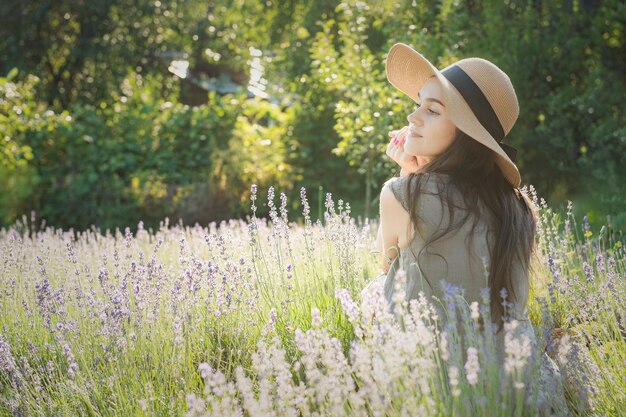 The girl in the hat sit in the middle of a lavender field