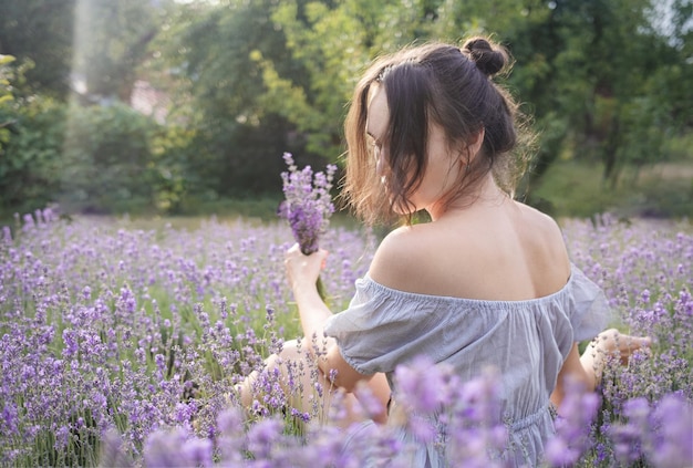 The girl in the hat sit in the middle of a lavender field