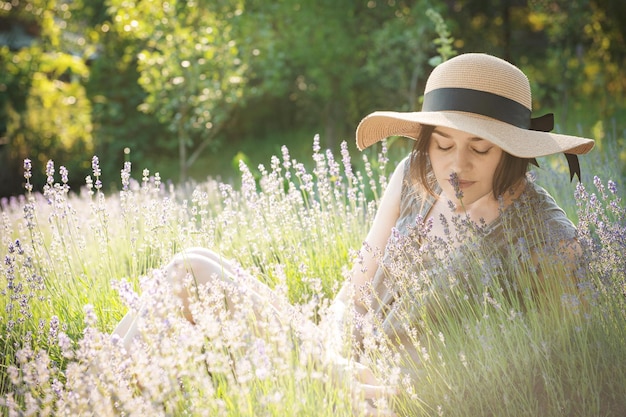 The girl in the hat sit in the middle of a lavender field