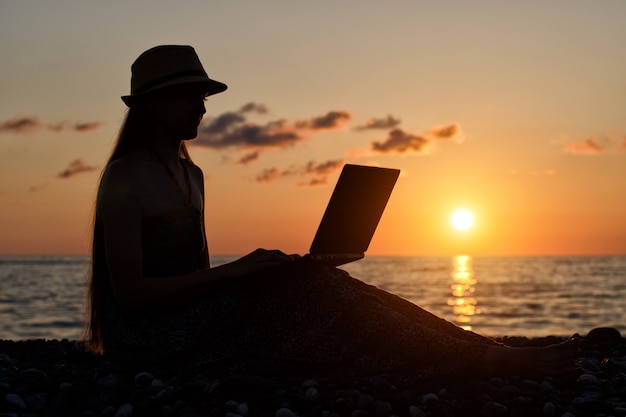 Girl in a hat sitting and working at her laptop