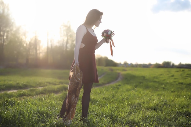 A girl in a hat on a walk in the park A girl with a basket walks in the spring Girl is walking along the road at sunsetxA