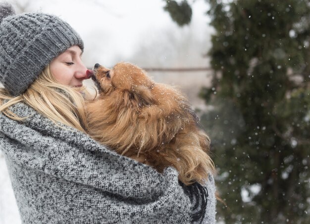 Girl having fun outside in snow with her dog Yorkshire Terrier. 