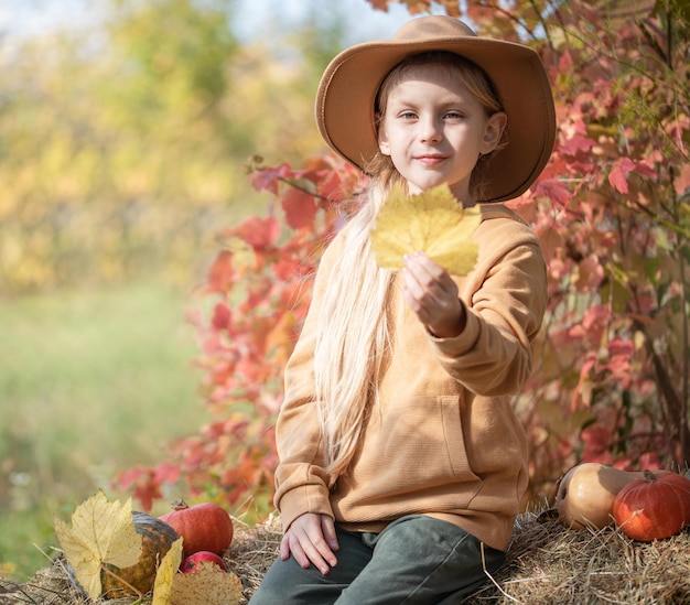 Girl in the hay with pumpkins