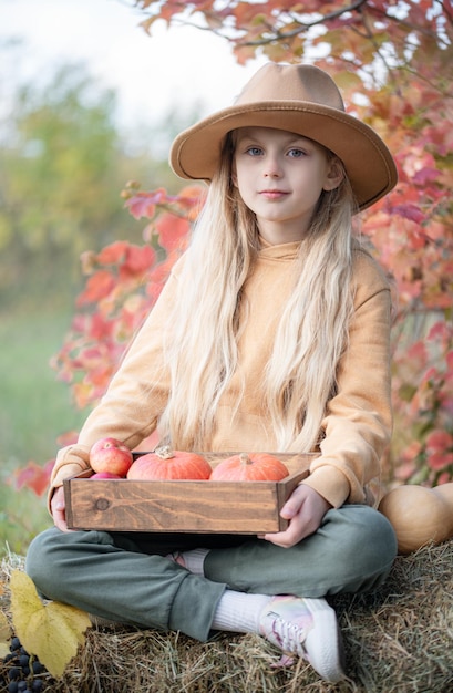 Girl in the hay with pumpkins