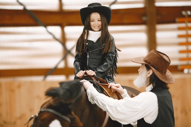 Girl in helmet Learning Horseback Riding. Instructor teaches little girl.