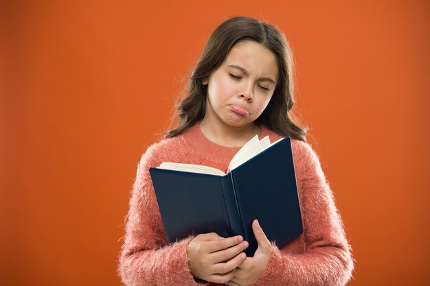 Girl hold book read story over orange background Child enjoy reading book Book store concept Wonderful free childrens books available to read Childrens literature Sad ending story