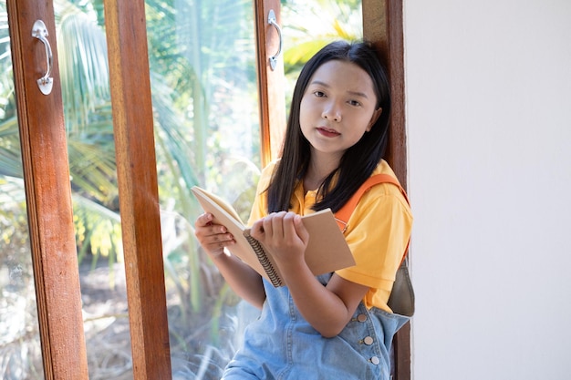 The girl hold the book sitting at wood windows at home