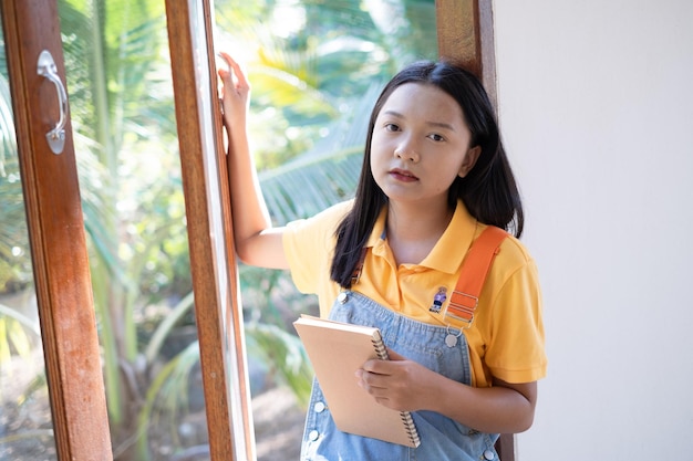 The girl hold the book sitting at wood windows at home