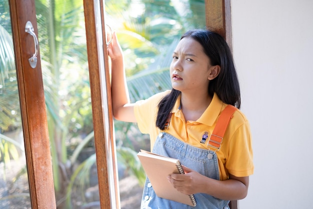 The girl hold the book sitting at wood windows at home