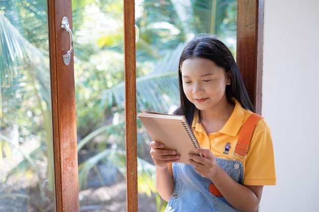 The girl hold the book sitting at wood windows at home