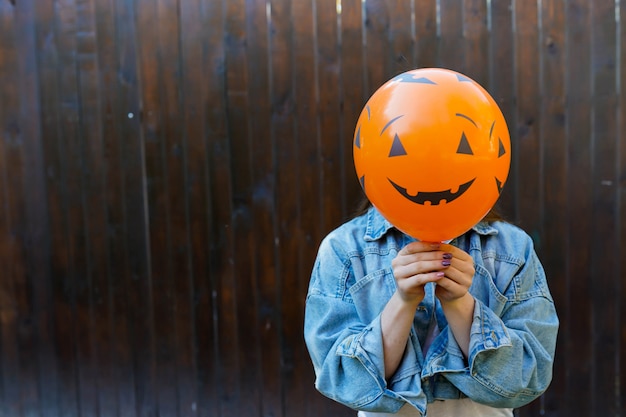 Girl holding ballon with pumpkin face