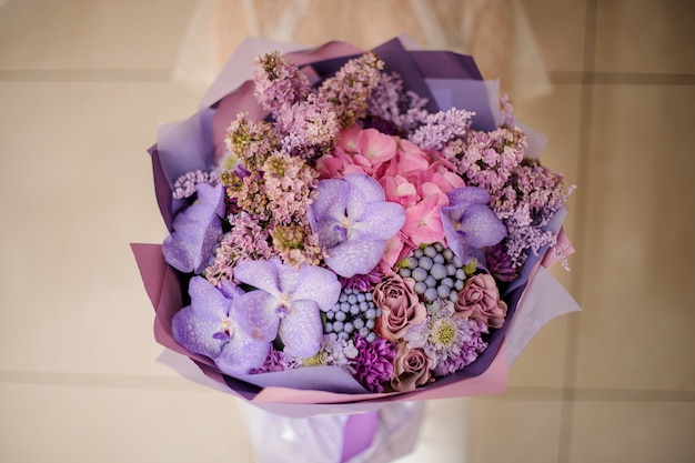 Girl holding a bouquet of tender lilac and orachids, and other spring flowers