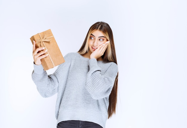 Girl holding a cardboard gift box and looks surprized.