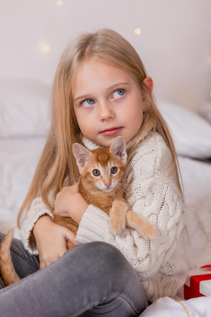 A girl holding a cat on a bed