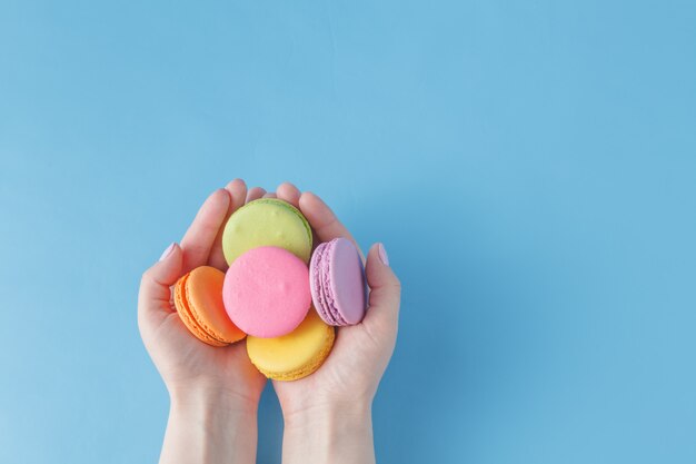 Girl holding colorful French macarons in hands