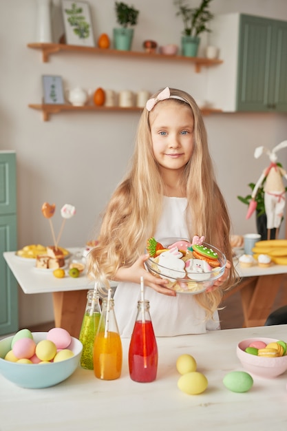 Girl holding Easter cookies at the kitchen