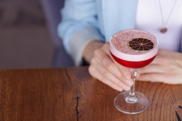 Girl holding a glass with a cocktail in a cafe or restaurant closeup restaurant concept