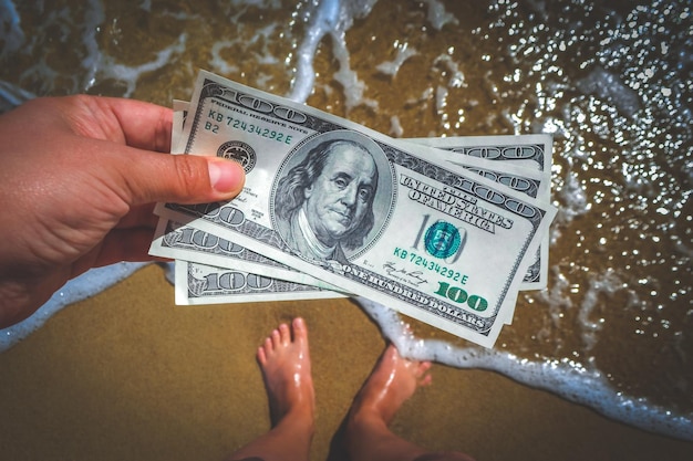 Girl holding money bill of 300 dollars on background of sea ocean