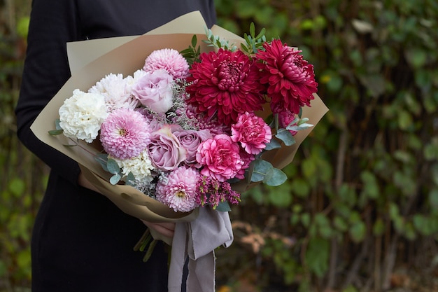 Girl holding pink and purple toned bouquet in vintage style outdoors opposite of the park