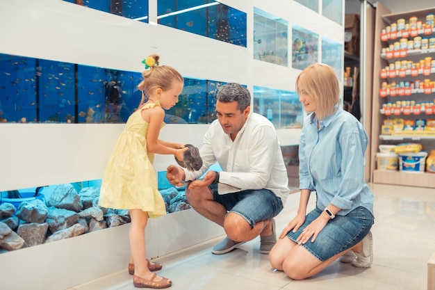 Girl holding rabbit while visiting pet shop with parents