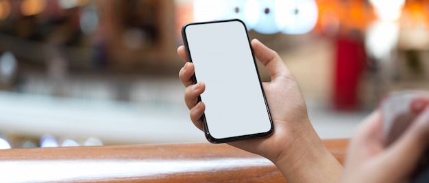 A girl holding  smartphone while standing at balcony in shopping mall