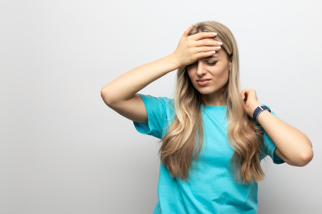 Girl holding on to a sore head on a white background