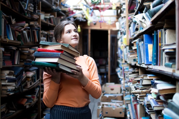 Girl holding a stack of books in the library