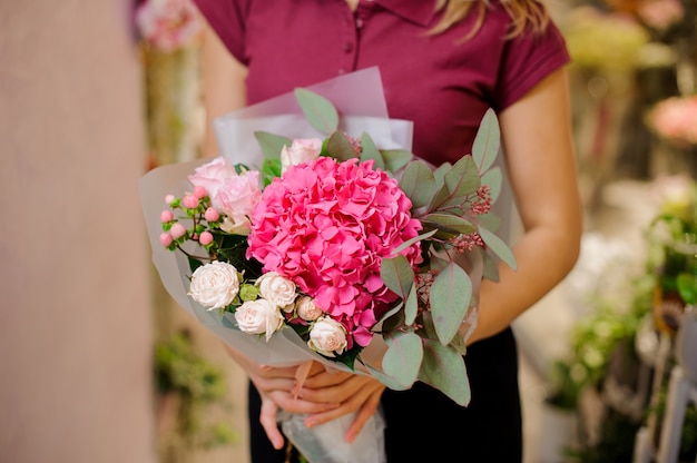 Girl holding a stylish bouquet of pink roses, hydrangea, eucalyptus