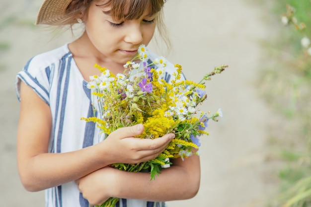 Girl holding wildflowers in the hands of a child