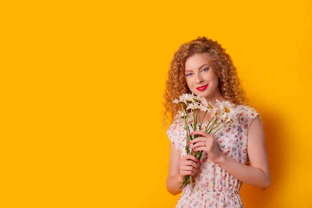 a girl holds a bouquet of daisies on yellow