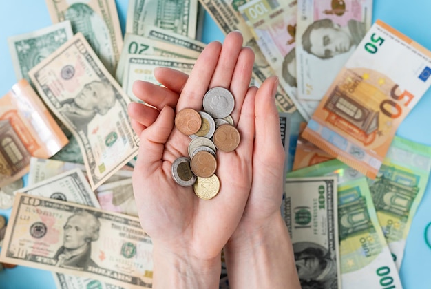 The girl holds coins in her hands against the background of scattered banknotes International banknotes dollars euros coins The concept of currency transactions loans exchange gambling