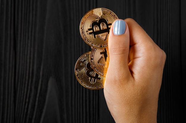 Girl holds a crypt in bitcoin his hand on a black wood background