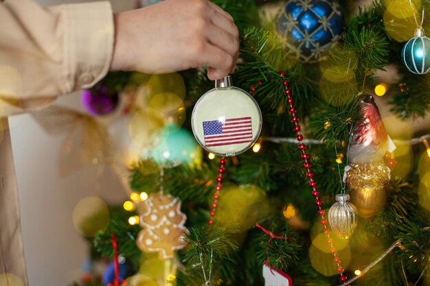 A girl holds a decoration on a Christmas tree with the flag of USA